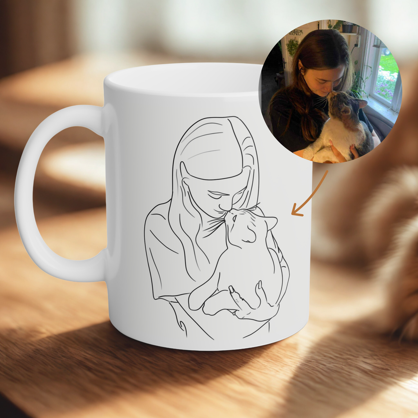 White mug with a line drawing of a woman holding a cat, placed on a wooden surface.